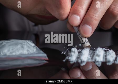 Begriff Drogensucht. Drogenmissbrauch, Mann nimmt Drogen, schnupft Kokainpulver, Nahaufnahme. Stockfoto