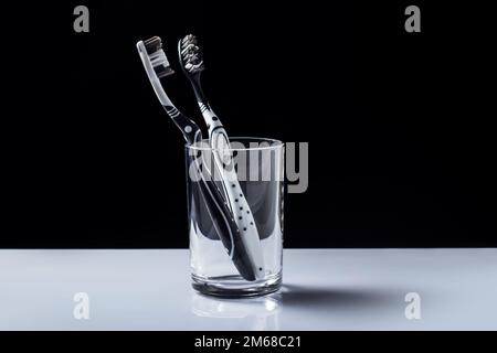 Zahnbürsten in einem Glas mit Kopierbereich auf schwarzem und weißem Hintergrund. Stockfoto