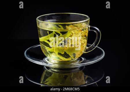 Eine Tasse grünen Tee und Linden auf schwarzem Hintergrund. Stockfoto