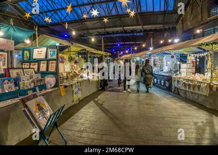 Ein abendlicher Blick auf die Menschen, die vor Weihnachten auf dem Canopy Market bei King's Cross spazieren. Stockfoto