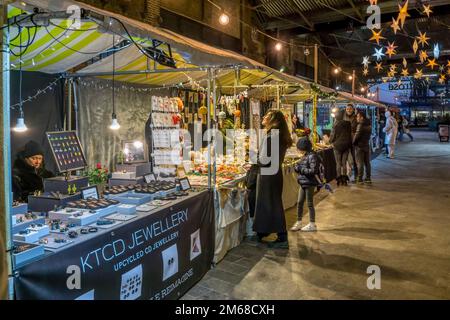 Ein abendlicher Blick auf die Menschen, die vor Weihnachten auf dem Canopy Market bei King's Cross spazieren. Stockfoto