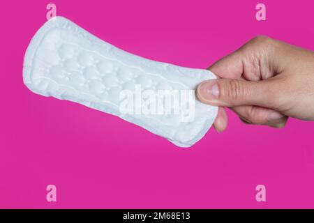Ein Mädchen, das sich in der Hand hält, ein Hygienepad auf rosa Hintergrund. Stockfoto