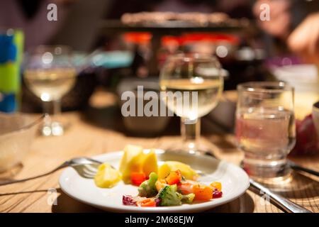 Bergheim, Deutschland. 31. Dezember 2022. Während einer Raclette-Mahlzeit an Silvester liegt Gemüse mit Käse auf einem Teller. Kredit: Viola Lopes/dpa/Alamy Live News Stockfoto