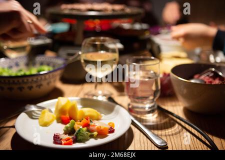 Bergheim, Deutschland. 31. Dezember 2022. Während einer Raclette-Mahlzeit an Silvester liegt Gemüse mit Käse auf einem Teller. Kredit: Viola Lopes/dpa/Alamy Live News Stockfoto