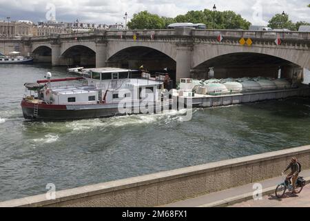 Ein Schiff, das unter einer Brücke an der seine im Zentrum von Paris vorbeifährt Stockfoto