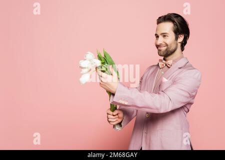 Positiver Veranstaltungsort in der Jacke mit einem Strauß Tulpen und Blick auf den pinkfarbenen Hintergrund, Stockbild Stockfoto