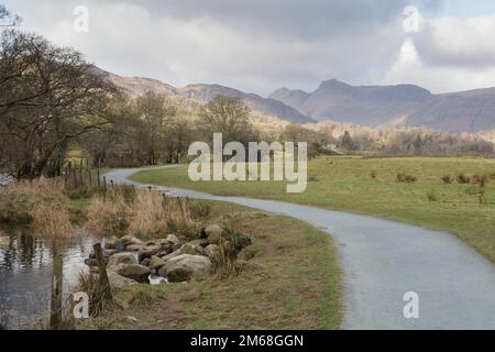 Am Ufer des Flusses Brathay in der Nähe von Elter Water im Lake District verläuft ein Fußweg. Mit den Langdale Hills im Hintergrund Stockfoto