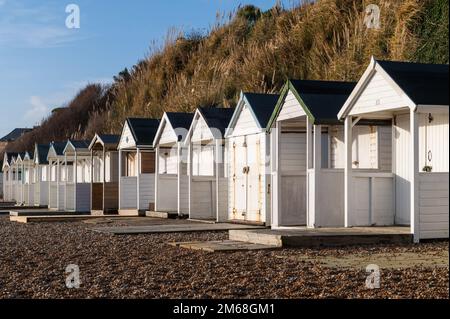 Weiße Holzhütten am Strand von Bexhill-on-Sea an einem sonnigen Tag Stockfoto