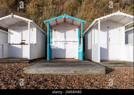 Drei weiße Holzhütten am Strand von Bexhill-on-Sea an einem sonnigen Tag Stockfoto