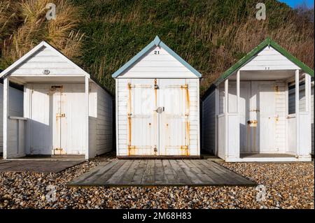 Drei weiße Holzhütten am Strand von Bexhill-on-Sea an einem sonnigen Tag Stockfoto