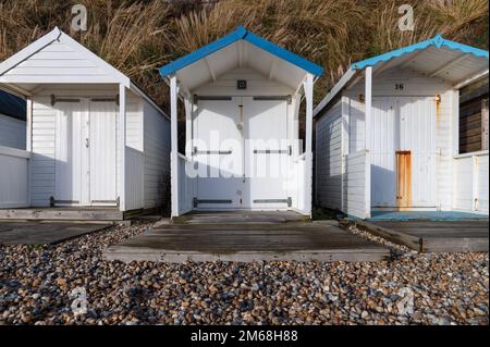 Drei weiße Holzhütten am Strand von Bexhill-on-Sea an einem sonnigen Tag Stockfoto