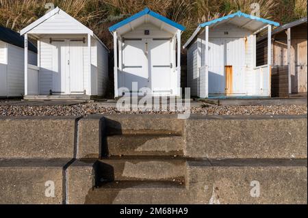 Drei weiße Holzhütten am Strand von Bexhill-on-Sea an einem sonnigen Tag Stockfoto