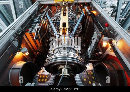 Der Motor eines Gasturbinenkompressors hängt während der Installation in einem Modul zur Stromerzeugung an einem Kran Stockfoto