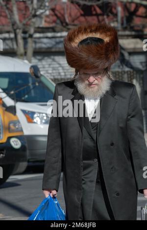 An einem späten Freitagnachmittag kommt ein orthodoxer jüdischer Mann mit Shtreimel nach Hause, nachdem er Essen für den Sabbat gekauft hat. In Brooklyn, New York. Stockfoto