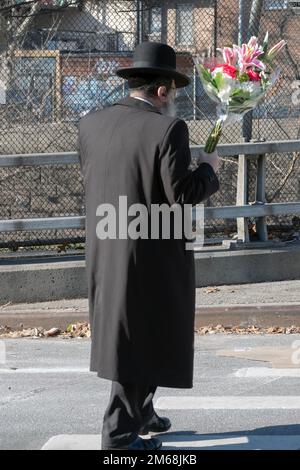 An einem Freitagnachmittag bereitet sich ein orthodoxer jüdischer Mann auf den Sabbat vor, indem er Blumen für sein Zuhause mitbringt. In Brooklyn, New York. Stockfoto