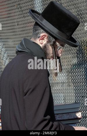 Ein ultraorthodoxer Jude mit langen Peyot-Geschäften für Bücher an einem Wintersonntag. In Brooklyn, New York. Stockfoto