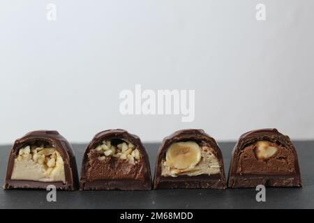 Schokoladen-corus-Süßigkeiten mit weißer Schokolade gefüllt mit Haselnüssen-Erdnuss-Praline-Ganache auf grauem Hintergrund mit Platz für Text und Stockfoto