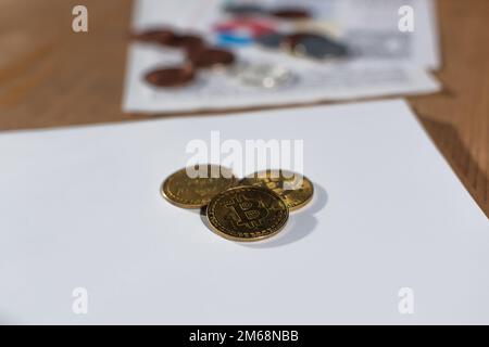 KIEW, UKRAINE - 17. NOVEMBER 2022: goldene Bitcoins auf weißem, leerem Notizbuch auf verschwommenem Büroschreibtisch Stockfoto