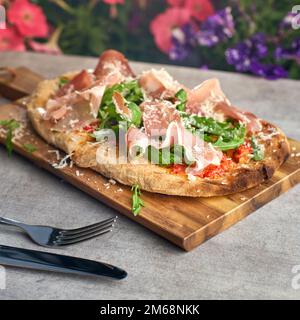 Frisch gebackene Focaccia oder Pizza mit Prosciutto Crudo und Rucola. Selektive Fokussierung. romanas Pizza. Stockfoto