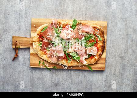 Frisch gebackene Focaccia oder Pizza mit Prosciutto Crudo und Rucola. Selektive Fokussierung. romanas Pizza. Stockfoto