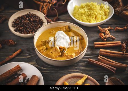 Hähnchen Tikka Masala scharfes Curryfleisch in einer Schüssel, serviert mit Reis auf Holzhintergrund. Stockfoto