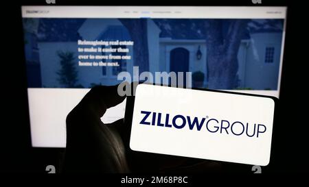 Person, die ein Smartphone mit dem Logo des US-Immobilienunternehmens Zillow Group Inc. Auf dem Bildschirm vor der Website hält. Konzentrieren Sie sich auf das Display des Telefons. Stockfoto