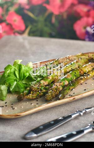 Gegrillter Spargel mit Erdnusssoße auf einem Teller. Selektiver Fokus. Stockfoto