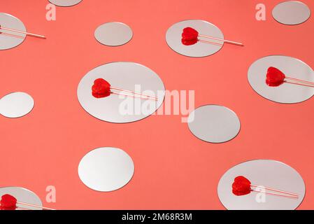 Rote herzförmige Lutscher auf runden Spiegeln. Minimale Liebe oder valentinskonzept. Stockfoto