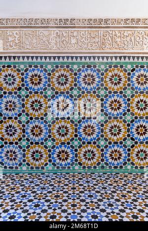 Ben Youssef Madrasa in Marrakesch war ein islamisches College. Die Wände und der Boden sind mit farbenfrohen Zellij-Fliesen in islamischen Mustern bedeckt. Stockfoto