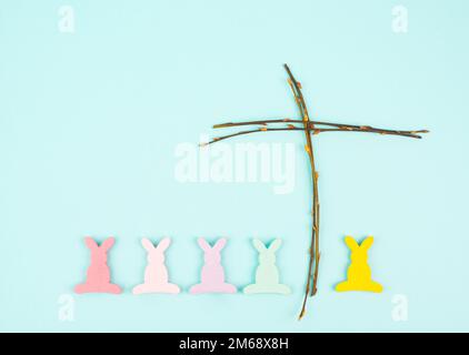Osterhasen oder Kaninchen mit einem religiösen Kreuz aus Weidenzweigen, christliche Frühlingsferien, Grußkarte Stockfoto