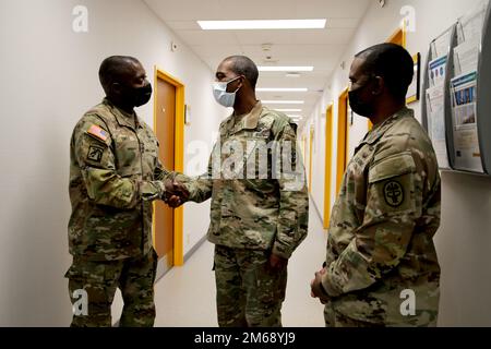 Generalleutnant R. Scott Dingle, links, Generalarzt der Armee und Kommandant der Medizin, Und MEDCOM Kommandosgt. Major Diamond D. Hough, rechts, überreicht eine Münze in DER SHAPE Healthcare Facility an LT. Oberst Simeon Smith, Leiter der öffentlichen Gesundheitseinrichtungen für DIE SHAPE und Brüssel, am 20. April 2022 in Casteau, Belgien. Stockfoto