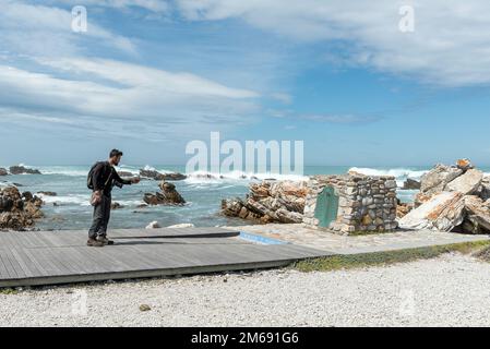 Agulhas-Nationalpark, Südafrika - 22. September 2022: Touristen machen Fotos mit dem Handy an der Tafel am Kap L'Agulhas, der südlichsten Spitze von AFR Stockfoto