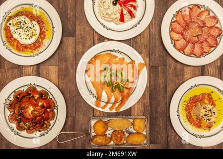 Ein wunderbarer Tisch voller Tapas-Speisen aus spanischen Bars, gemischte Kroketten, Thunfischbauch, Tomatensalat, geräucherter Lachs, Kotelettsteak und russischer Salat Stockfoto