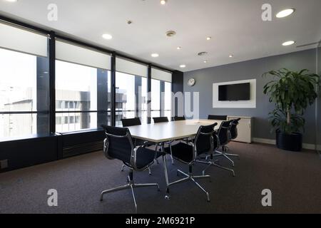 Moderner Sitzungssaal eines modernen Büros mit langem Holztisch mit Drehstühlen und neuem Teppichboden Stockfoto