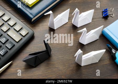 Papierschwarzer Schwan und weiße auf dem Bürotisch als unvorhersehbares Ereignistheorie-Konzept. Stockfoto