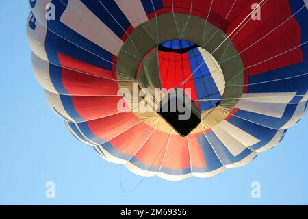 Der Heißluftballon mit Korb steigt am Himmel auf Stockfoto