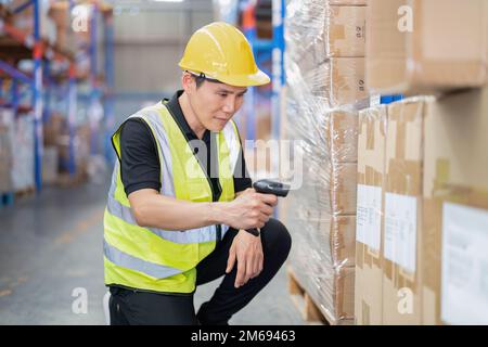 Mitarbeiter, die in einem großen Lagerlager arbeiten, halten die Scannerbox für den drahtlosen Barcode-Scanner im Regal Stockfoto