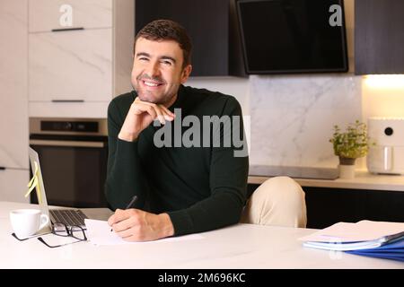 Ein Mann, der mit Stift und Papier im Home Office schreibt Stockfoto