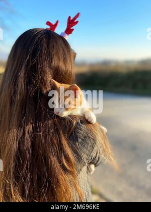 Kätzchen sitzt auf der Schulter des Mädchens, draußen Stockfoto