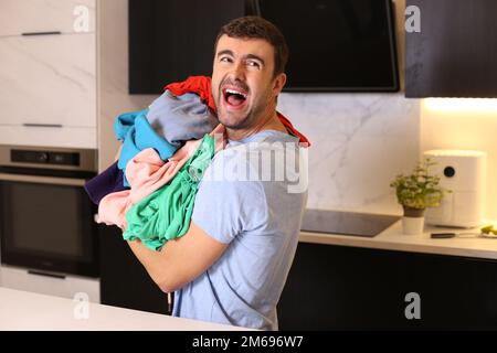 Gestresster Mann, der einen Haufen schmutzige Sachen in der Hand hat Stockfoto