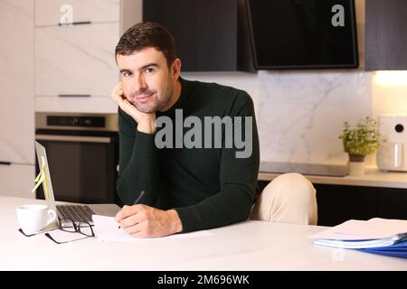 Ein Mann, der mit Stift und Papier im Home Office schreibt Stockfoto