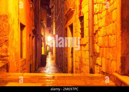 Beleuchtete, enge Straße der Altstadt. Straßenbeleuchtung von Dubrovnik in der Nacht Stockfoto