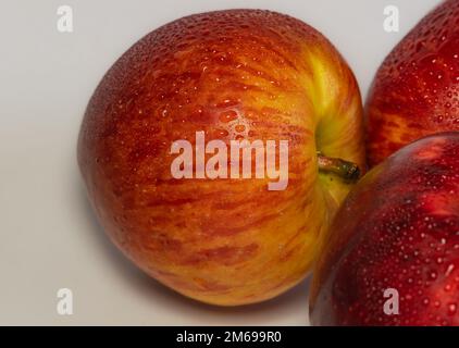 Wunderschöne Nahaufnahme von rotem Apfel auf weißem Hintergrund mit verschwommenem Hintergrund. Roter Apfel mit Wassertropfen auf weißem Hintergrund. Stockfoto