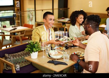 Eine multikulturelle Gruppe von Freunden isst im Restaurant zu Abend. Stockfoto