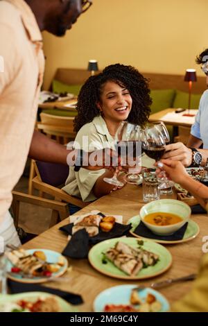 Zwischenmenschliche Freunde stoßen auf den Erfolg in einem Restaurant mit Rotwein an. Stockfoto