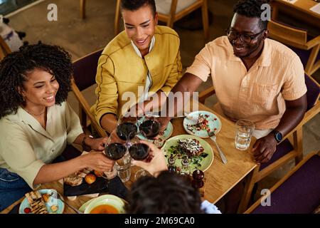 Blick von oben auf eine Gruppe von Freunden, die ein glückliches Ereignis während einer Dinnerparty in einem Restaurant feiern. Stockfoto