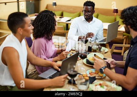 Geschäftsleute, die sich die Finanzen anschauen, berichten, dass ein afrikanischer Geschäftsmann eine Beteiligung hält. Stockfoto