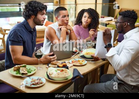 Die Geschäftsleute sitzen in einem Restaurant und halten während des Abendessens ein Geschäftstreffen ab. Stockfoto