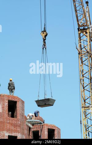 Hebekran zum Anheben eines Ziegelsteins im Obergeschoss eines Unterbaugebäudes Stockfoto