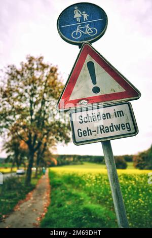 Fußgänger und Radfahrer teilen sich ein Straßenschild mit dem Aufdruck „Bürgersteig“ mit deutschem Text und vertikalem Schuss Stockfoto